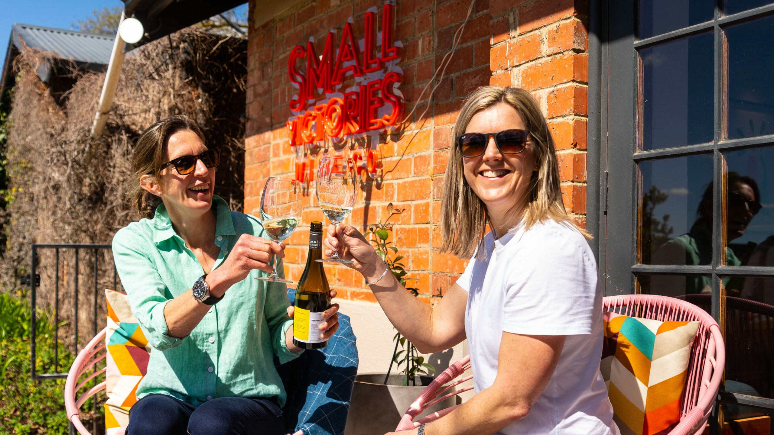 Jules Ashmead and Bec Ashmead in front of Small Victories cellar door cheers